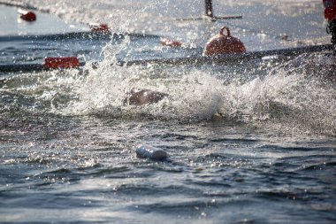 Bir adam suda yüzüyor ve su sıçrıyor. Su berrak ve sakin. Adam beyaz bir gömlek giyiyor.
