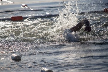 Bir yüzücü suyun içindedir, su sıçratır ve dalgalanmalar yaratır. Yüzeyde yüzen birkaç beyaz nesneyle su sakin ve berrak. Huzurlu ve huzurlu bir sahne.