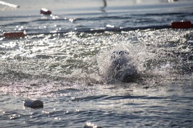 Arka planda birkaç şamandıra ile okyanusta bir damla su. Su sakin ve güneş parlıyor.
