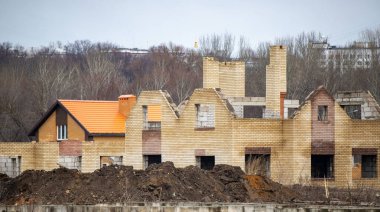 Bir sürü tuğla ve bir sürü pencereyle bir ev inşa ediliyor. Ev bir tarlanın ortasında.