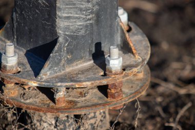 Üzerinde bir sürü cıvata olan paslı bir metal boru. Sürgüler paslanmış ve borular kirlenmiş.