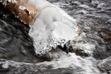 A large piece of ice is floating in a river. The ice is surrounded by water and he is melting. The scene is serene and peaceful, with the ice creating a beautiful contrast against the dark water