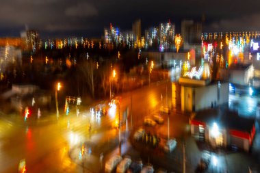 Geceleri birçok ışık ve arabanın olduğu bulanık bir şehir manzarası. Sahne meşgul ve hareketli.