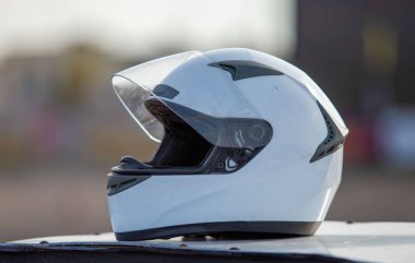 A white motorcycle helmet sits on a white surface. The helmet is clean and shiny, and it is positioned in a way that it is facing the camera. Concept of safety and protection