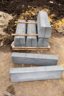 Bir yığın gri tuğla üst üste istiflenmiş. Tuğlalar ahşap bir palette.