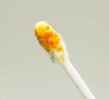 A yellow and white toothbrush with yellow bristles. The bristles are frayed and the toothbrush is covered in yellow powder