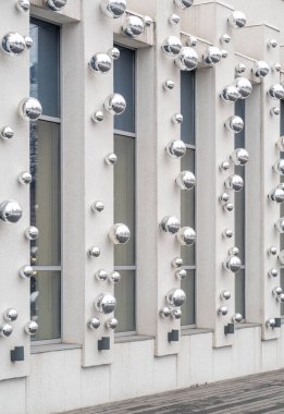 A building with a lot of shiny, metallic spheres on it. The spheres are arranged in a way that creates a sense of movement and energy. The building appears to be a modern, industrial structure