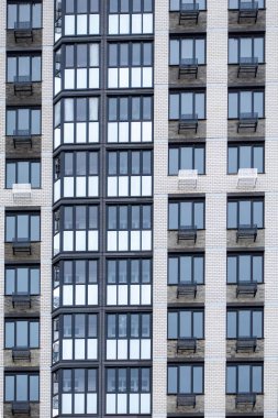 Bir sürü penceresi ve kliması olan büyük bir bina. Bina çok yüksek ve bazı pencereleri açık olan birçok penceresi var. Pencereler satırlarda sıralanmıştır