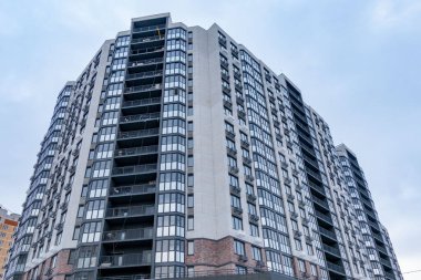 A large building with many windows and a grey brick facade. The building is tall and has a modern design