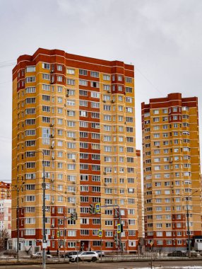 Bir sürü penceresi olan iki uzun kahverengi ve kırmızı bina. Binalar arabalı ve trafik lambalı bir caddenin yanında.