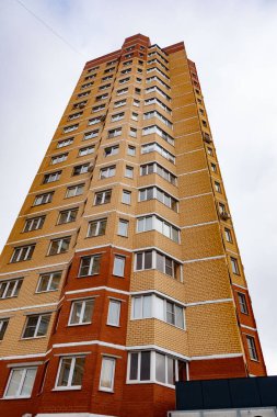 Bir sürü penceresi olan uzun kahverengi bir bina. Bina çok yüksek ve bir sürü penceresi var.