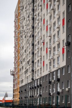 Kırmızı ve beyaz süslemeli büyük bir apartman. Bina yüksek ve birçok penceresi var.