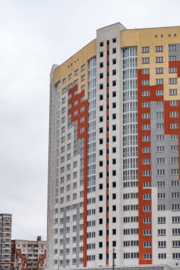 Üzerinde kırmızı ve beyaz şerit olan yüksek bir bina. Bina çok yüksek ve birçok penceresi var.