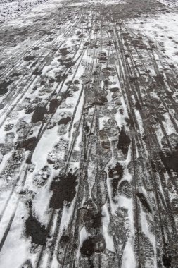 Lastik izleriyle kaplı bir kar yolu. İzler kuyrukta ve çok uzunlar.
