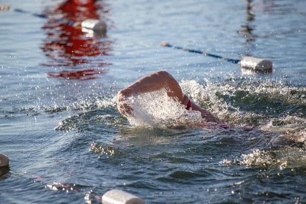 Suda bir yüzücü var ve su mavi. Yüzücü kırmızı bir gömlek giyiyor.