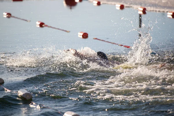 Suda bir yüzücü var ve su onun etrafına sıçrıyor. Sahne canlı ve enerjik, yüzücü aktiviteden zevk alıyor.