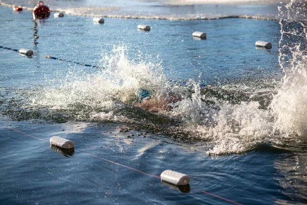 Suda beyaz bir şamandırayla havuzda yüzen bir adam var. Su sıçrıyor ve şamandıra yüzüyor.