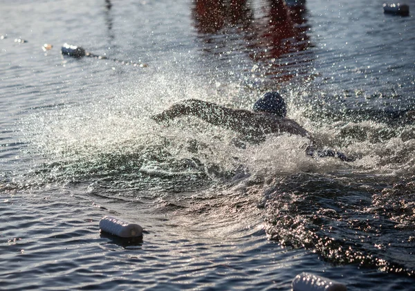 Yakınlarda bir şişeyle suda yüzen bir adam var. Su bulanık ve etrafta bir sürü plastik şişe yüzüyor.