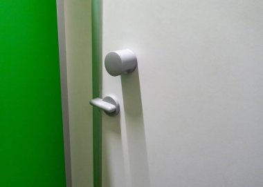 Gümüş düğmeli ve gümüş saplı bir kapı. Kapı tokmağı yuvarlak ve gümüşken, sapı da gümüş renktedir ve benzer bir şekle sahiptir. Kapı beyaz malzemeden yapılmıştır.