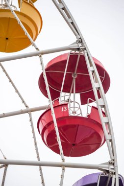 A colorful Ferris wheel with a red and white one labeled 13. The wheel is surrounded by a white frame