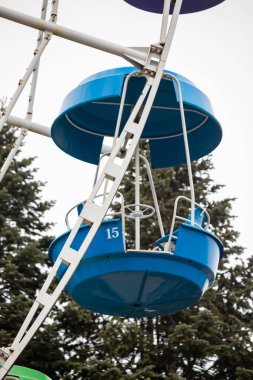 A blue and white merry go round with the number 15 on it. The ride is in a forest