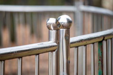 A metal fence with two silver balls on top of it. The fence is surrounded by a green area