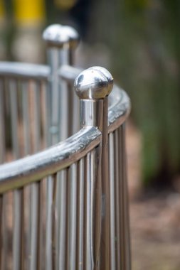 A metal fence with a silver ball on top of it. The fence is surrounded by a lot of trees and bushes