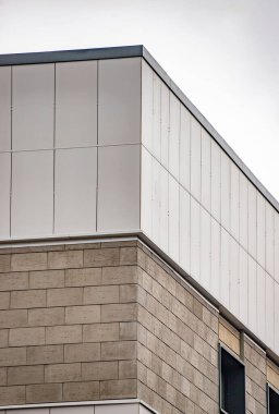 A building with a white roof and a gray brick wall. The roof is slanted and the wall is made of bricks
