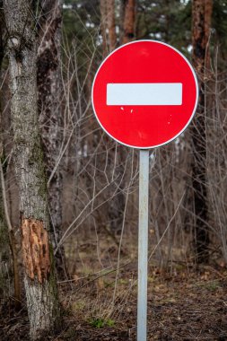 A red and white sign with a white line in the middle. The sign is in a forest
