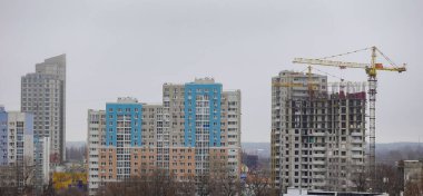 Arka planda vinç olan bir gökyüzü. Binalar uzun ve mavi. Gökyüzü bulutlu ve gri