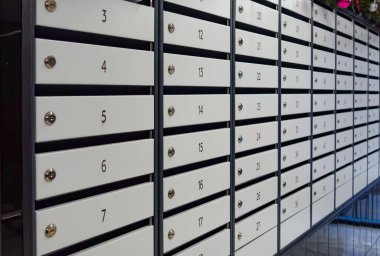 A row of white mailboxes with numbers on them. The numbers are arranged in a row and are numbered from 1 to 24