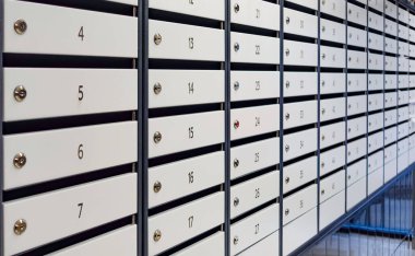 A row of white mailboxes with numbers on them. The numbers are arranged in a row and are numbered from 1 to 24