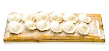 A wooden board with a pile of doughnuts on it. The doughnuts are white and appear to be freshly made