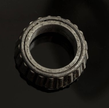 Ortasında delik olan siyah ve gri bir metal nesne. Yuvarlak bir nesne. Cisim parlak ve metalik bir görünüme sahip.