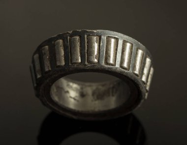 Siyah bantlı gümüş ve siyah bir yüzük. Yüzüğü bir erkek takıyor. Yüzük eski ve yıpranmış.