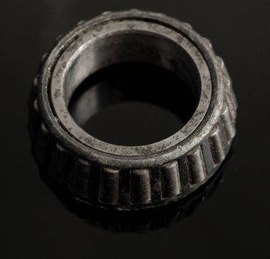 A black and grey metal ring with a hole in the middle. The ring is worn and has a worn look to it