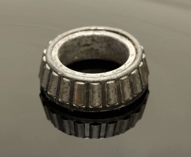 A worn out, rusted, and dirty looking metal object with a black and silver color. It is a small, round object with a black and silver color