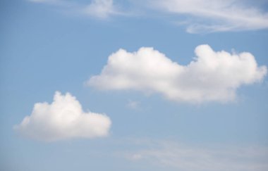 White cumulus clouds look large against the blue sky.