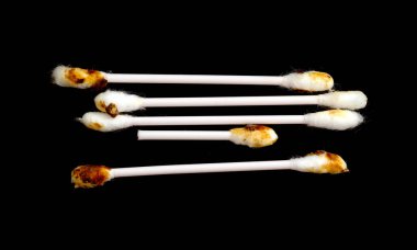 A close up of a bunch of used cotton swabs. The swabs are brown and have a burnt tip