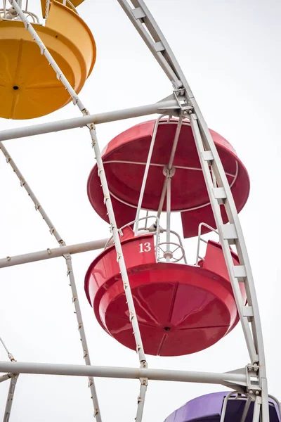 A colorful Ferris wheel with a red and white one labeled 13. The wheel is surrounded by a white frame