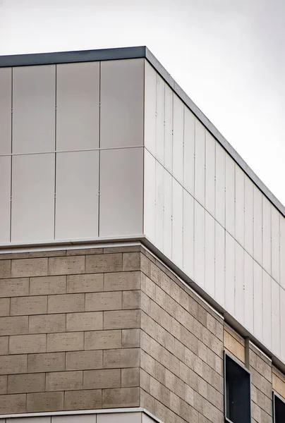 A building with a white roof and a gray brick wall. The roof is slanted and the wall is made of bricks