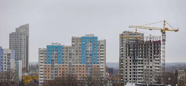 Arka planda vinç olan bir gökyüzü. Binalar uzun ve mavi. Gökyüzü bulutlu ve gri