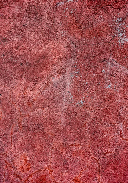 A red wall with a rough texture. The wall is covered in dirt and has a worn appearance