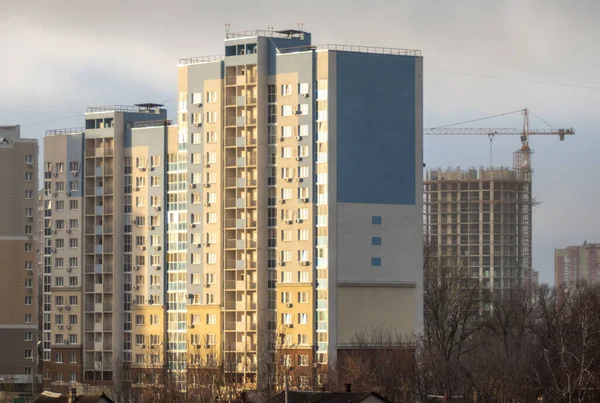 Arka planda vinç olan büyük mavi bir bina. Gökyüzü bulutlu ve güneş binanın üzerinde parlıyor.