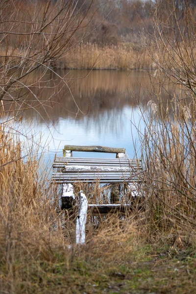 Uzun otlarla çevrili bir gölde ahşap bir rıhtım var. Rıhtım boş ve su sakin. Görünürdeki tek nesne rıhtım olduğu için manzara sakin ve sakin.