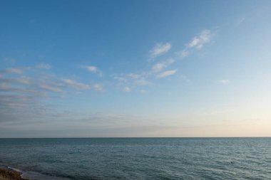 Gökyüzü bulutsuz ve masmavi. Okyanus sakin ve huzurlu. Sahne huzurlu ve rahatlatıcı.