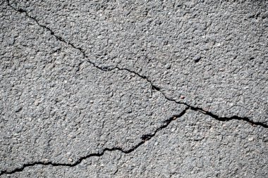 Çatlak ve çatlamış beton bir yüzey. Çatlaklar derin ve geniştir ve yüzey pürüzlüdür. Olay yeri yıkım ve çürüme ile dolu, çünkü beton hasar görmüş.