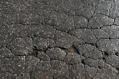 İçinde delik olan çatlak ve bozuk bir yol. Yol bakımsız ve araba kullanmak için güvenli değil.