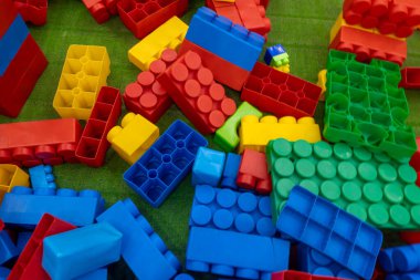 Yeşil bir yüzeyde renkli legolar yığını. Legolar farklı renk ve boyutlarda ve tüm yüzeye yayılmışlar. Oyunculuk ve yaratıcılık kavramı