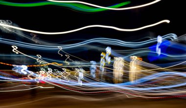 Görüntü bulanık, rengarenk bir şehir caddesi tasviri. Arabaların ve binaların ışıkları bir hareket ve enerji hissi yaratırken renkler...